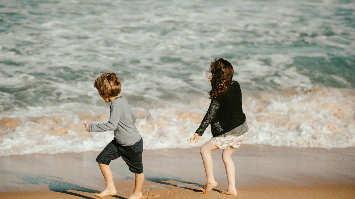 two young children playing on the beach near the ocean