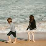 two young children playing on the beach near the ocean